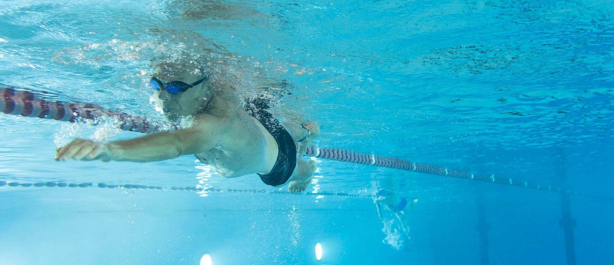 Mann schwimmt Bahnen im Sportbecken