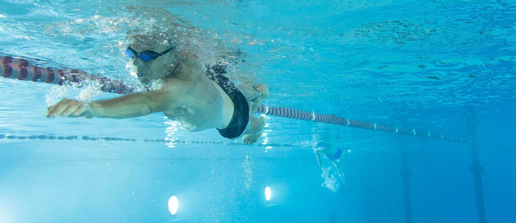 Mann schwimmt Bahnen im Sportbecken