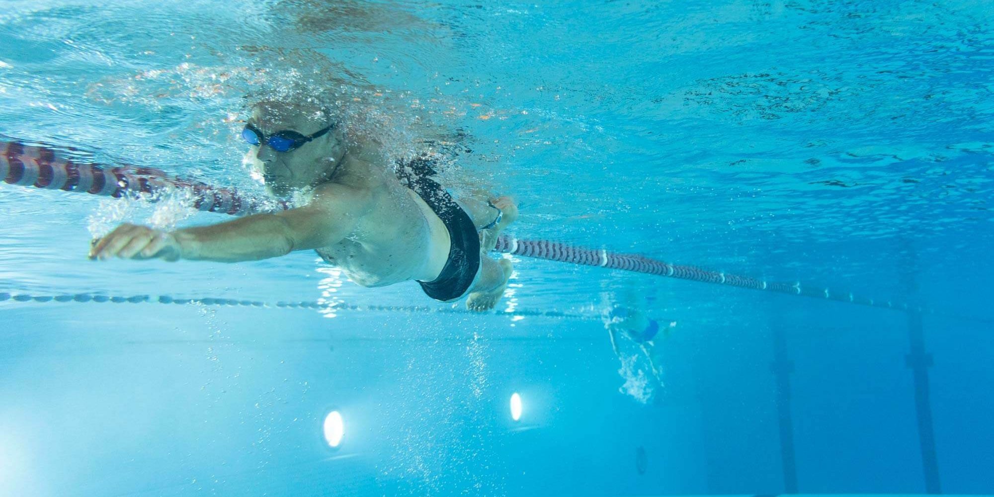 Mann schwimmt Bahnen im Sportbecken