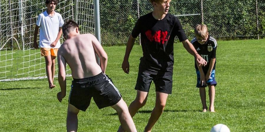 Kinder spielen Fussball auf der Wiese im Aussenbereich