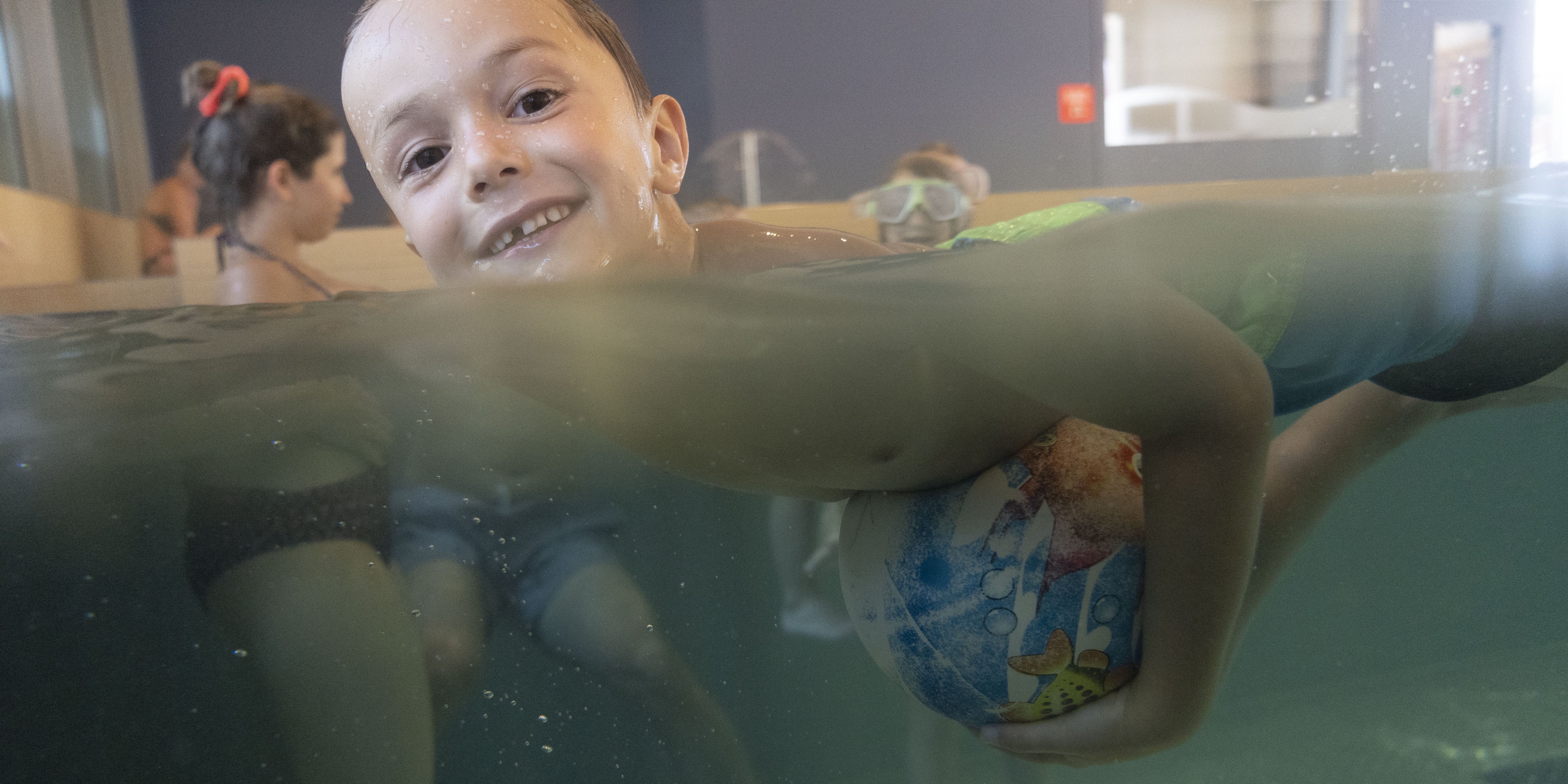 Kinder spielen im Hallenbad mit einem Ball
