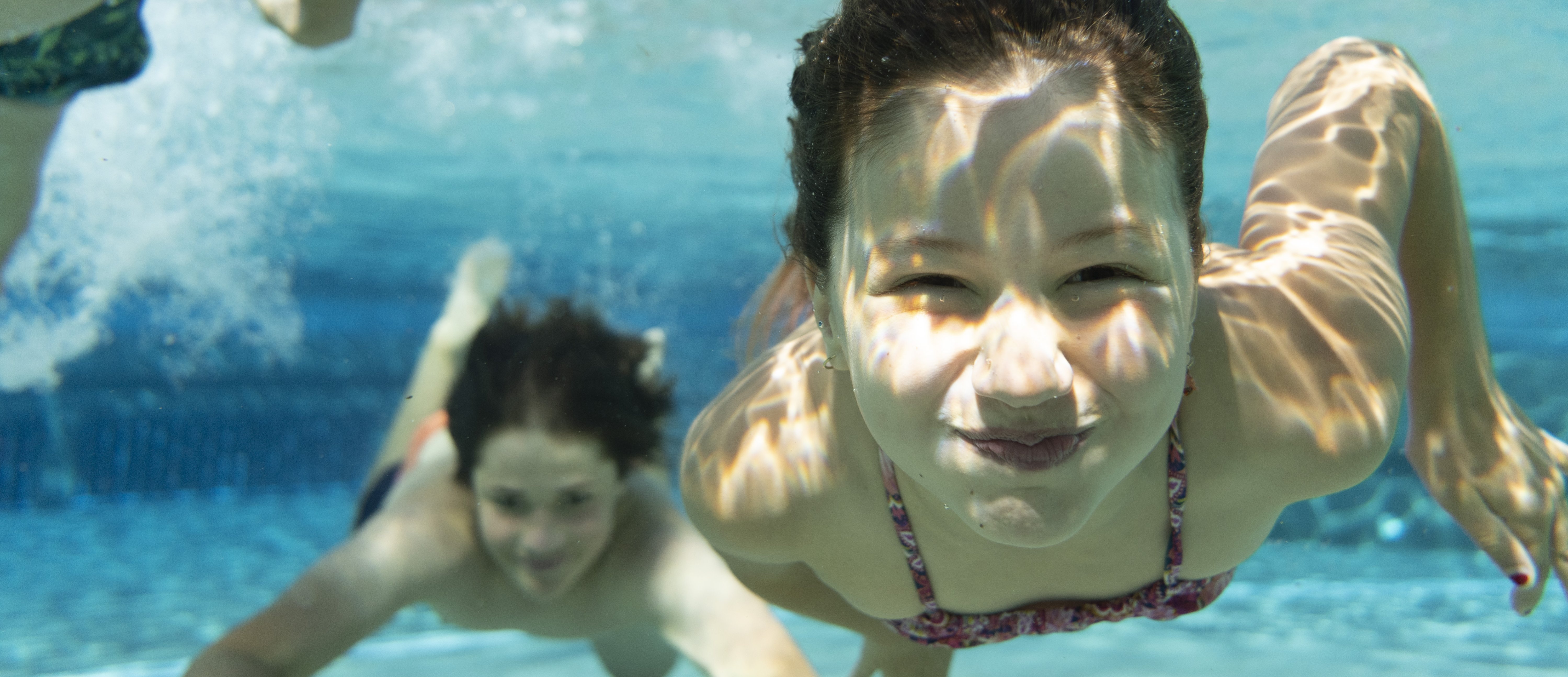 Kinder tauchen unter Wasser im Hallenbad