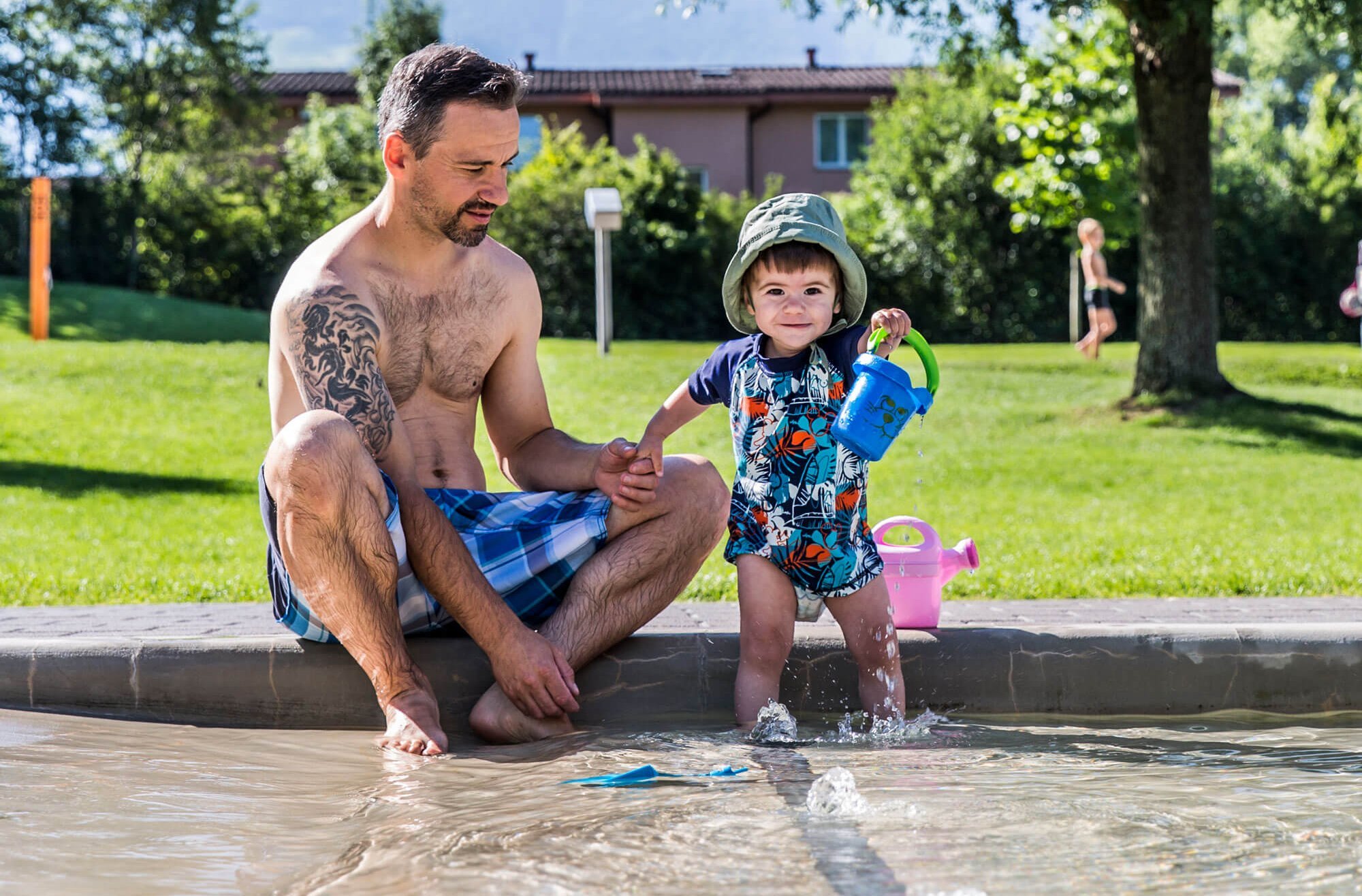 Vater spielt mit Kleinkind im Outdoor-Planschbecken